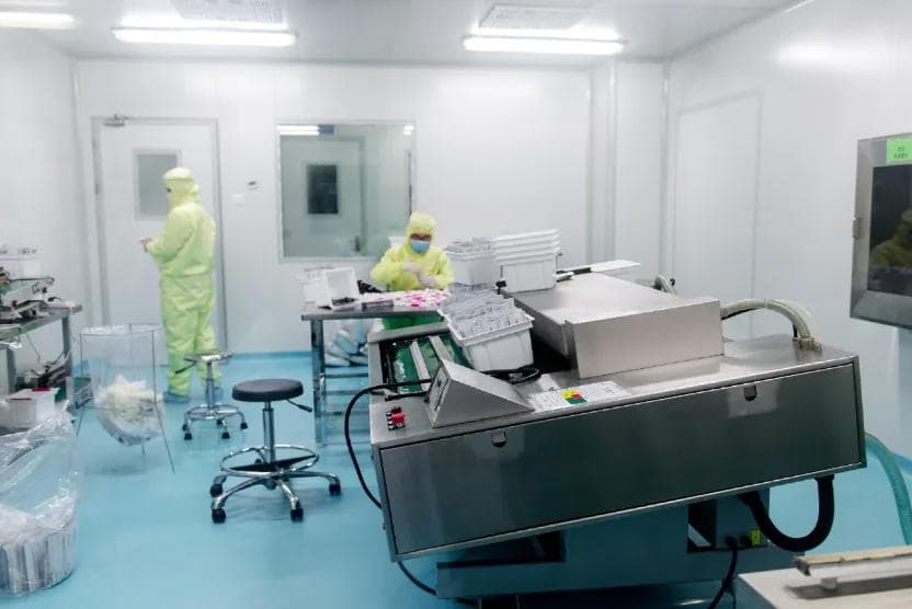 Technicians in protective clothing working on instrumentation in a controlled environment